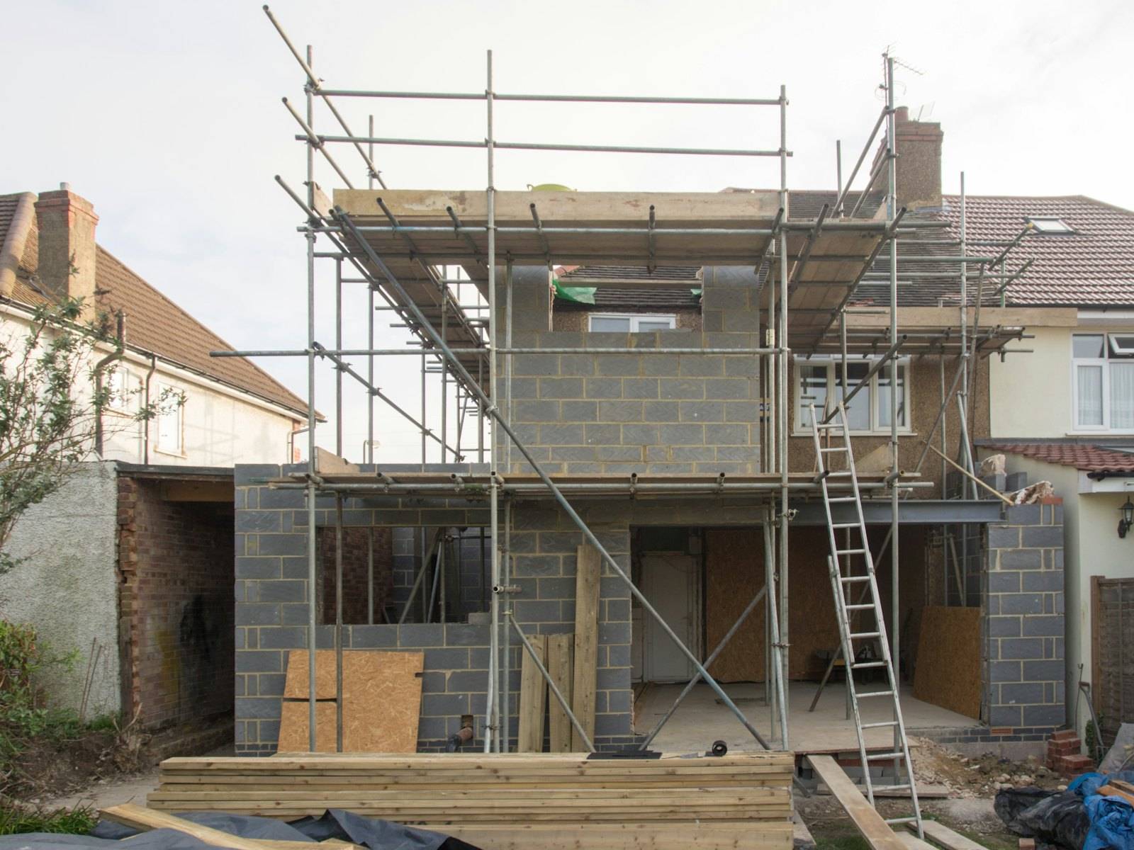 Extension maçonnée en construction sous échafaudage, à l'arrière d'une maison