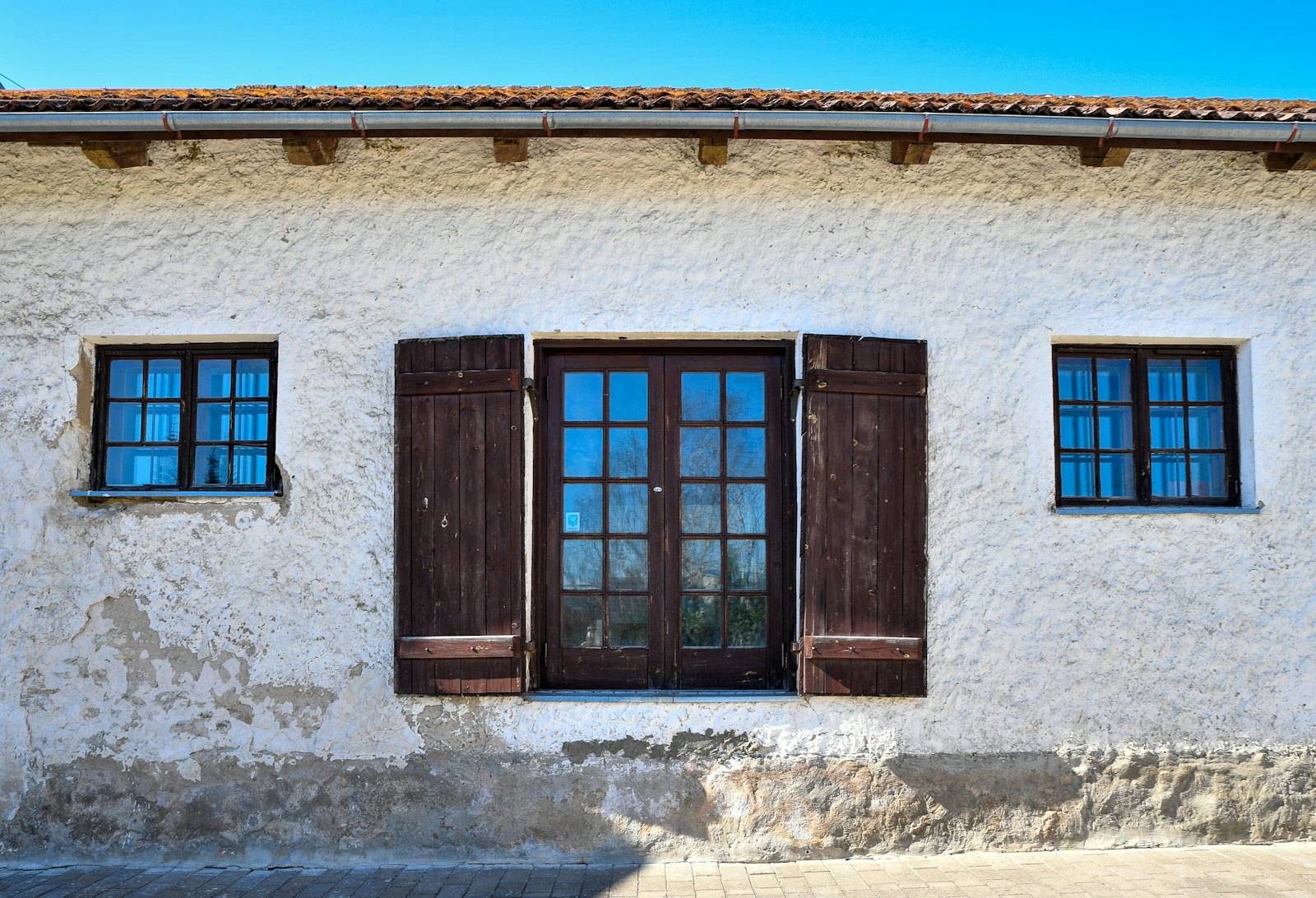 Façade enduite d'une maison ancienne aux volets en bois