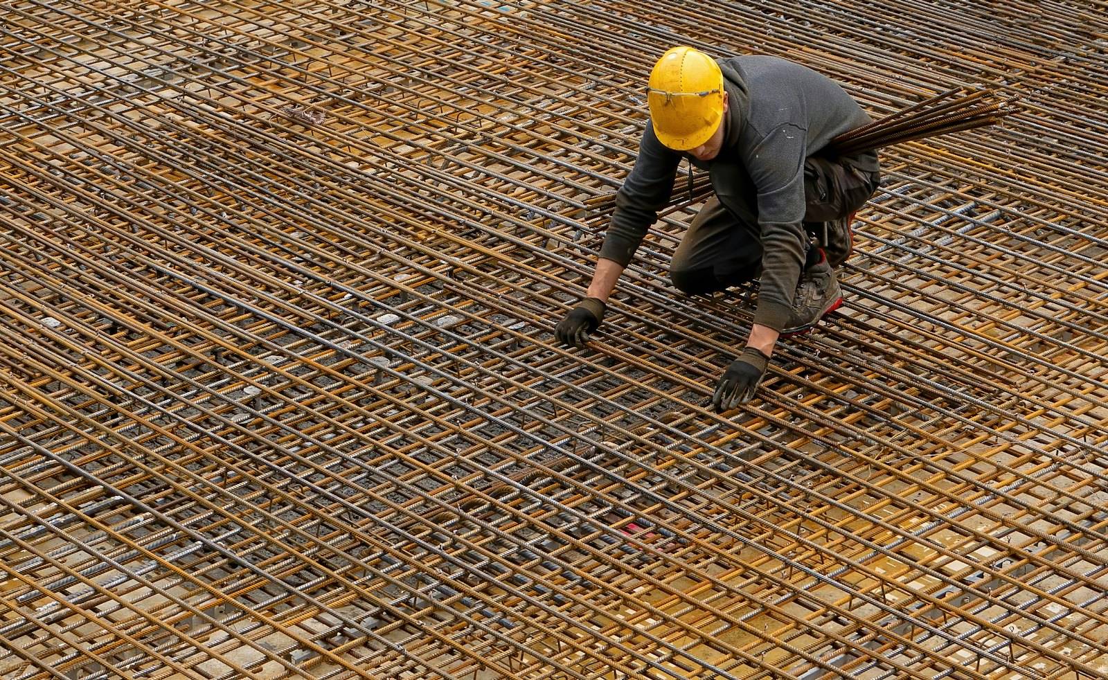 Ouvrier ligaturant un treillis d'armatures avant le coulage d'une dalle
